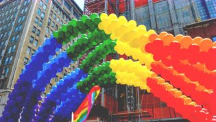 rainbow colored balloons arched in the shape of a rainbow at pride parade event